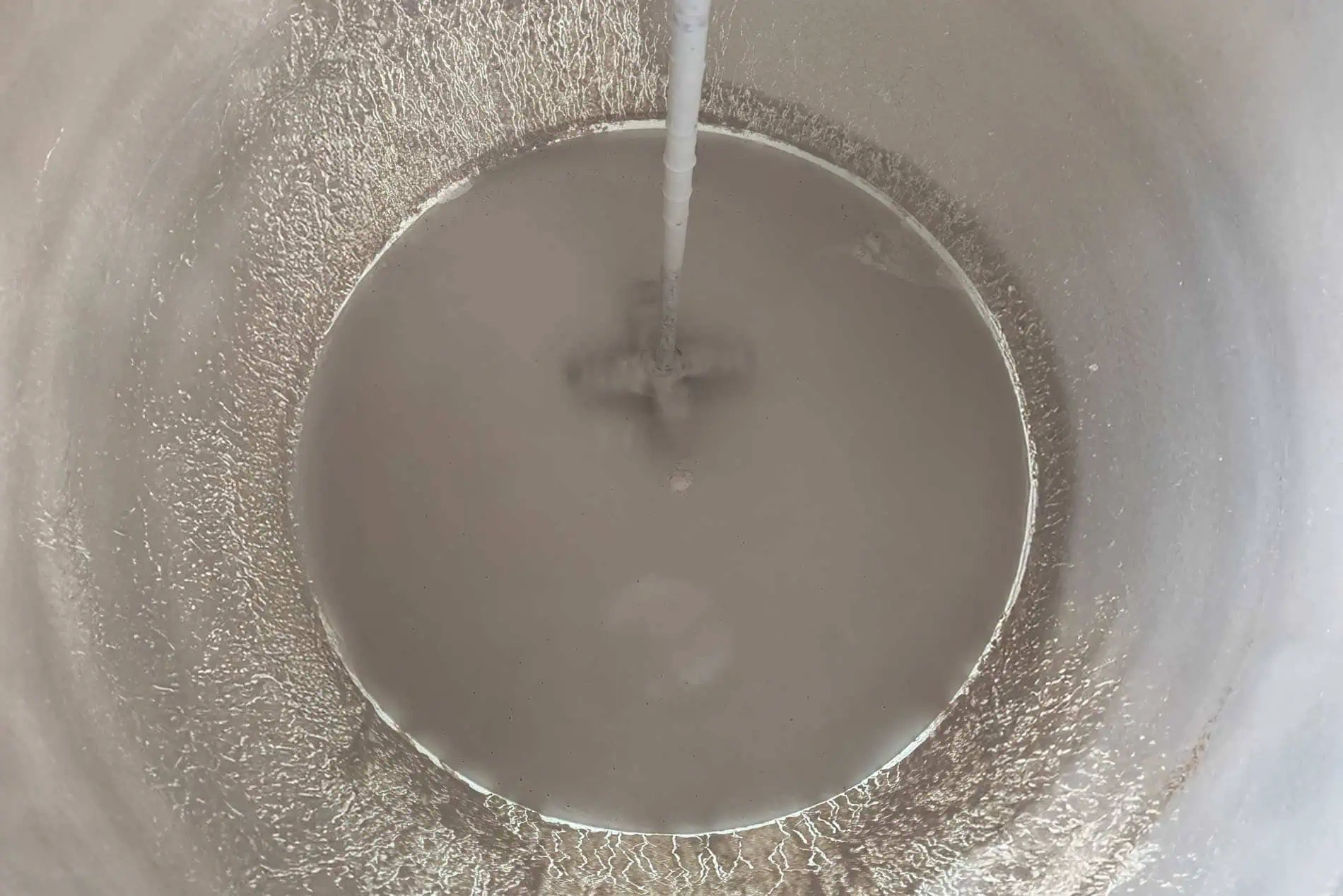 Mixing gray liquid in a large container.